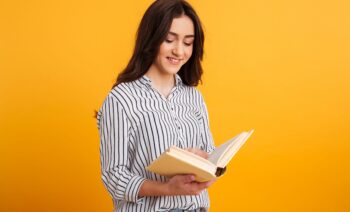 Image of Smiling brunette woman in shirt reading book Image of Smiling brunette woman in shirt reading book over yellow background