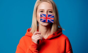 beatiful girl holds British flag in hand beatiful girl holds British flag on blue background